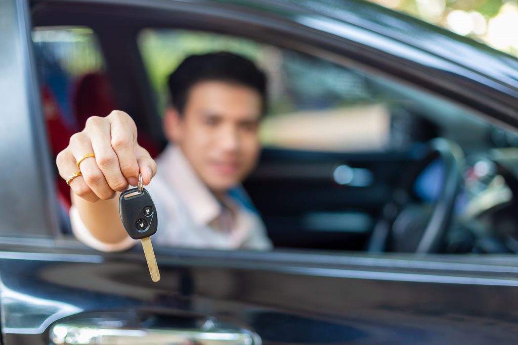 Young handsome man with car key remote geting information on diminished value for his leased vehicle